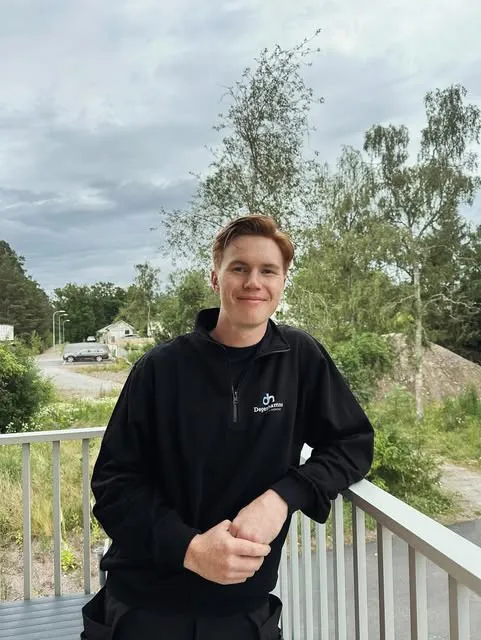 Leende montör i svart tröja med Degerhamns VVS logotyp, lutad mot ett räcke