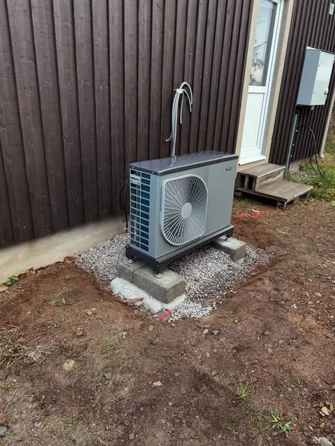 Luft/vatten-värmepump utomhus, placerad på en nygjord grund av sten och grus